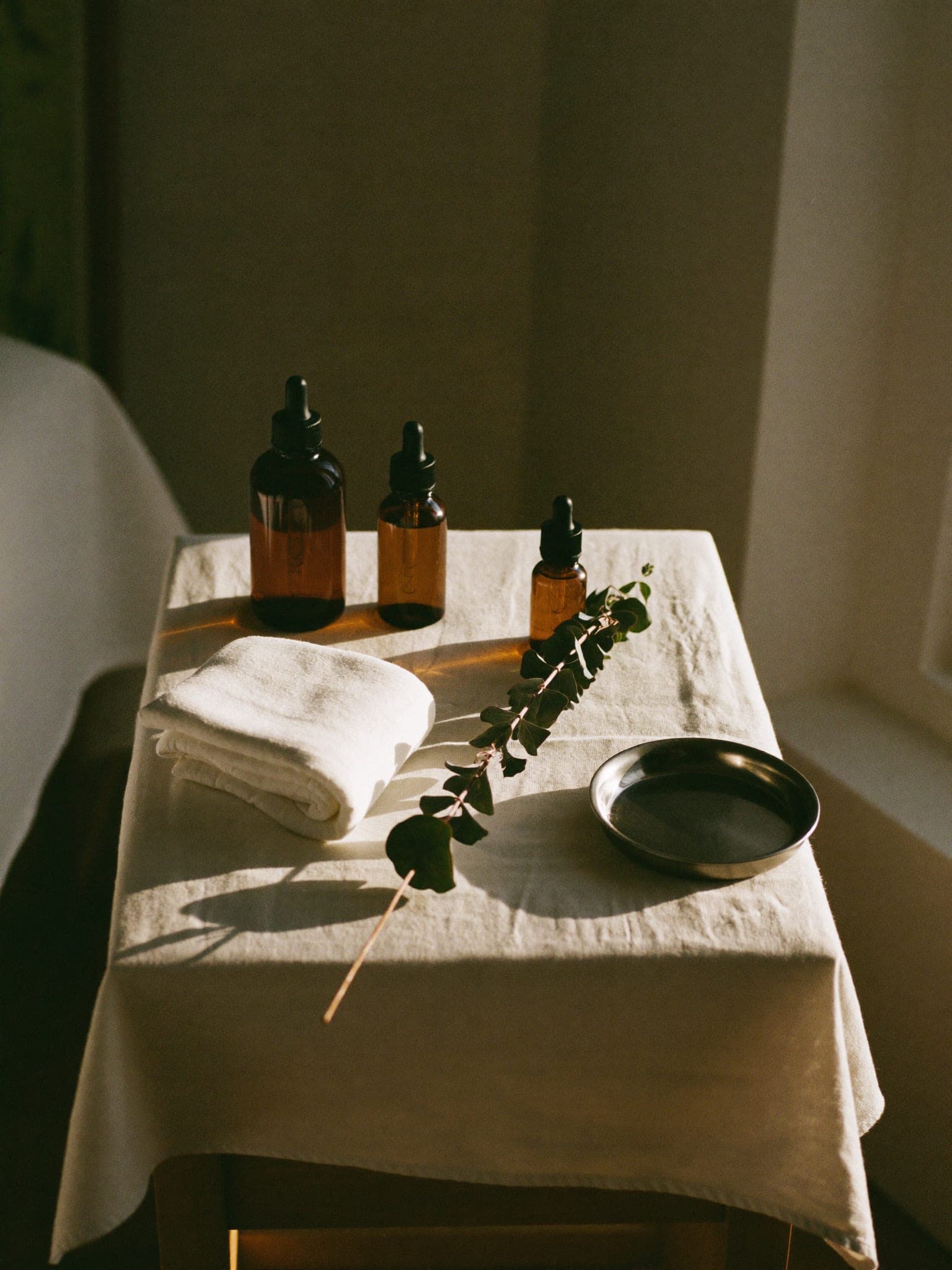 A treatment trolley laid with amber dropper bottles, folded gauze and a sprig of eucalyptus