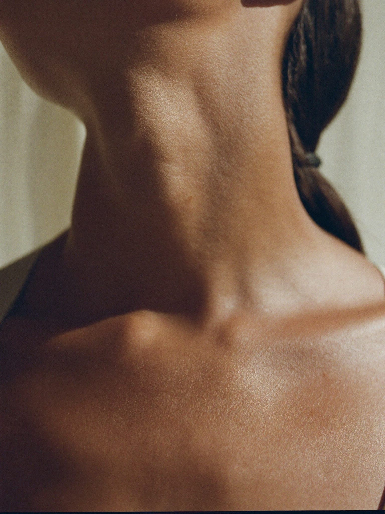 A close study of a neck and collarbone in directional daylight, face out of frame