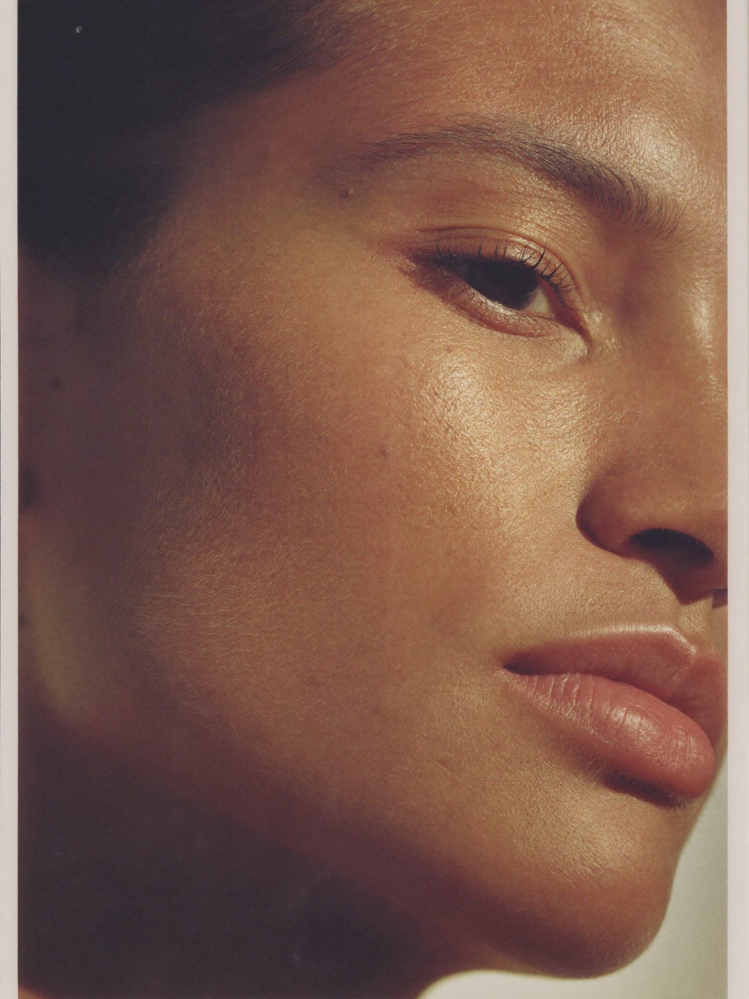 A close view of a person's cheek and closed eye in warm daylight, skin texture visible